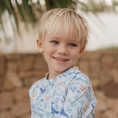 Close up of a little boy wearing the Little Dutch Long-Sleeve Rash Vest Ocean Dreams Blue