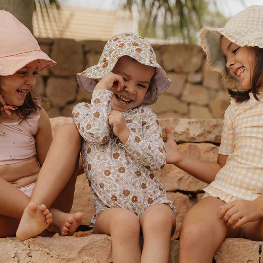 Little Girl Wearing The Little Dutch Long-Sleeve Swimsuit Vintage Little Flowers and matching Sun hat 