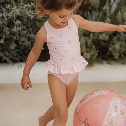 Little girl playing wearing the Little Dutch Swimming Costume in pale pink with Rosy Meadows print