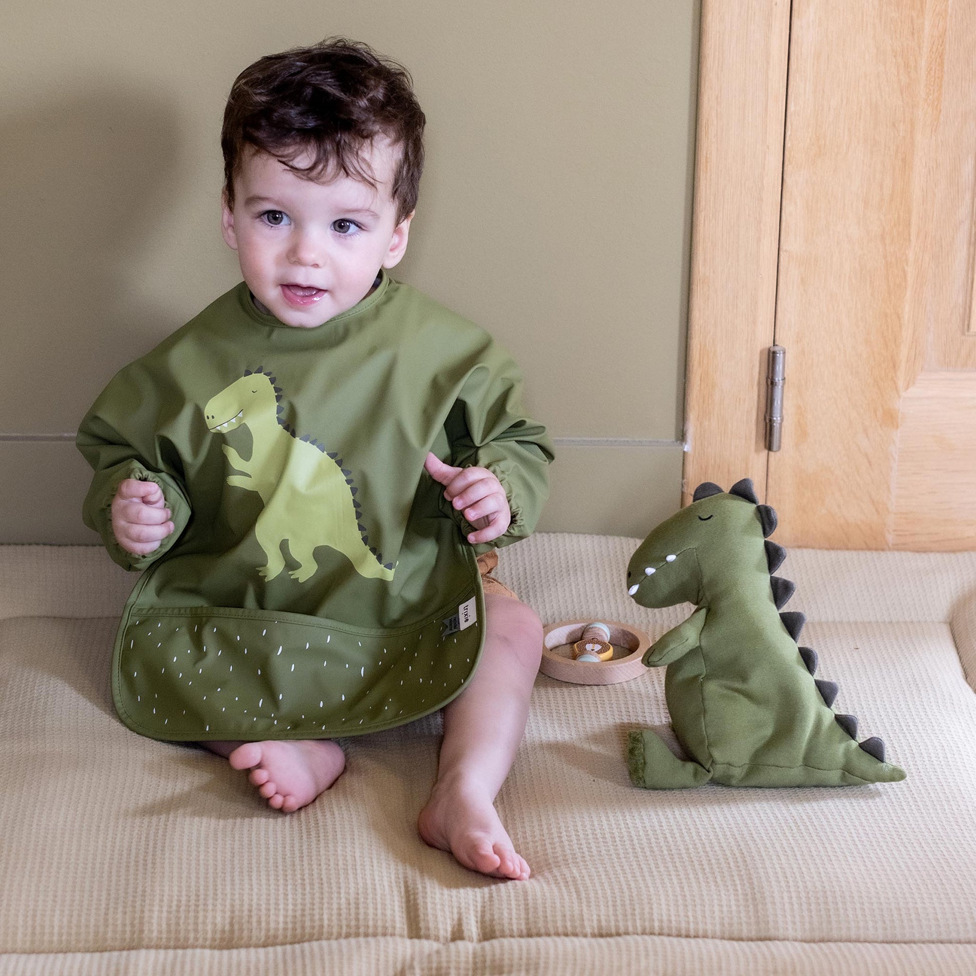 Little boy wearing Trixie Waterproof long sleeve bib - Mr. Dino